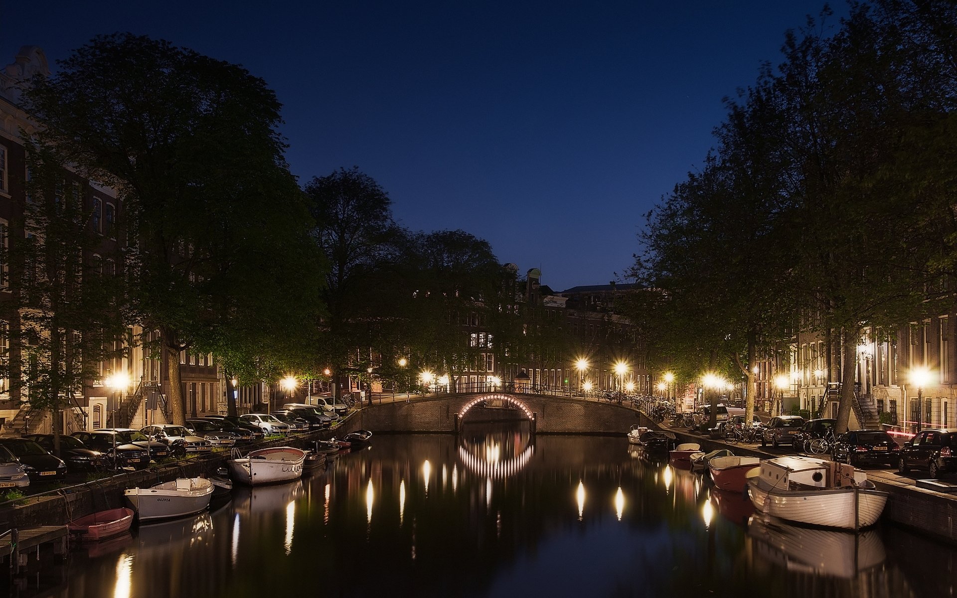 HD PC desktop wallpaper: man-made Amsterdam canal at night, illuminated bridges and houseboats reflecting on calm water.