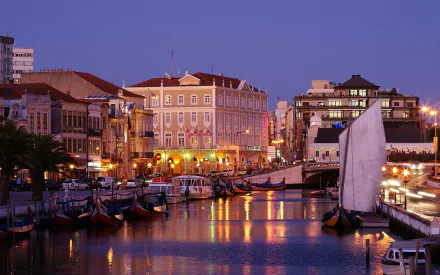 HD desktop wallpaper showcasing the man-made canals and historic buildings of Aveiro at twilight, with boats reflecting on calm waters.