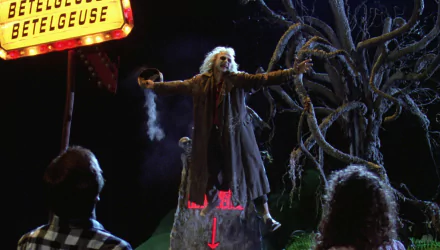 HD PC desktop wallpaper featuring a scene from the movie Beetlejuice with the character Beetlejuice standing dramatically with outstretched arms under a marquee sign.