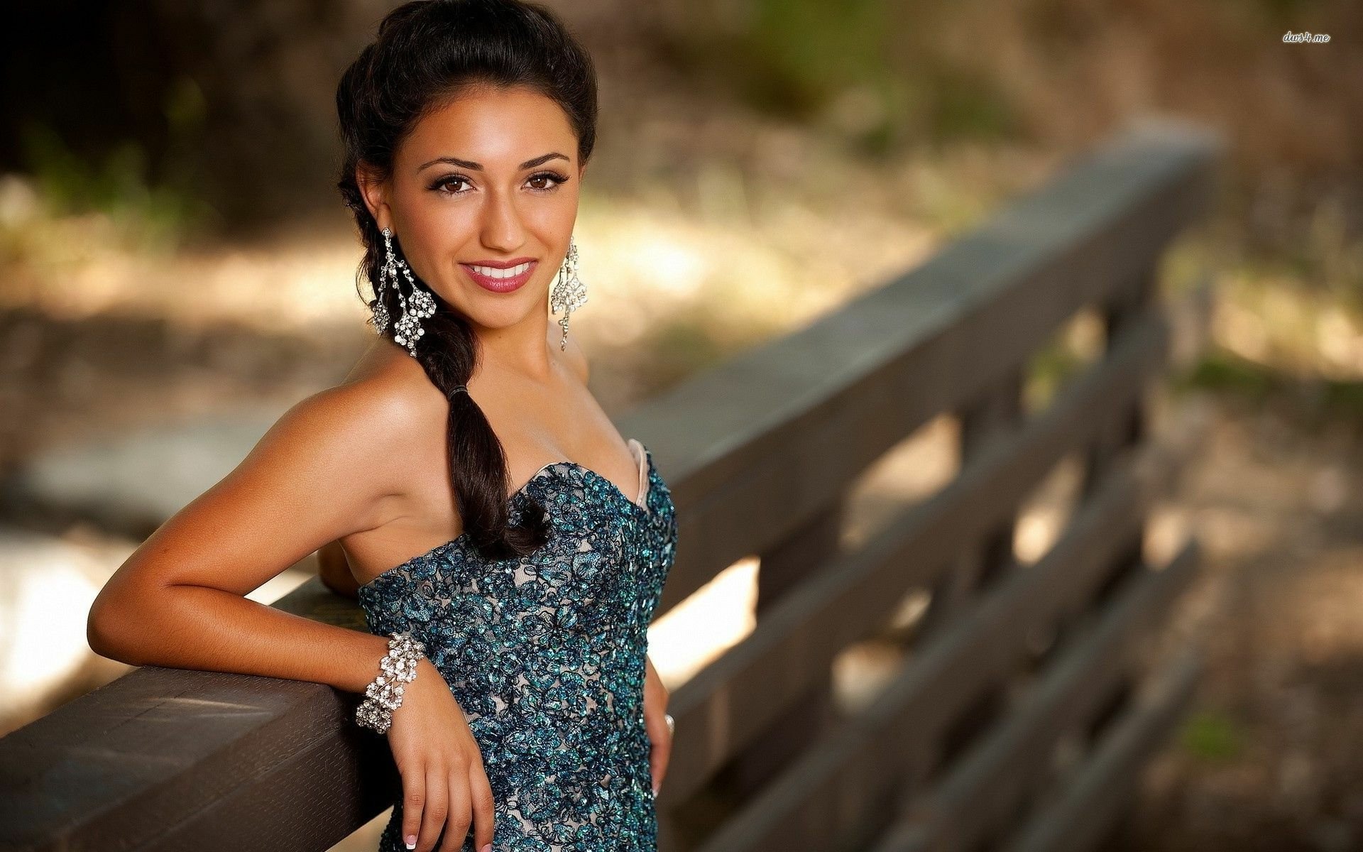 HD PC desktop wallpaper featuring a smiling woman in an elegant dress and statement jewelry, posing outdoors with a serene, natural background and a reflective mood.
