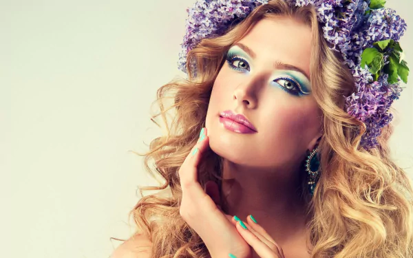 A woman with curly hair adorned with a lilac flower wreath poses with her hands near her face in this HD desktop wallpaper and background.