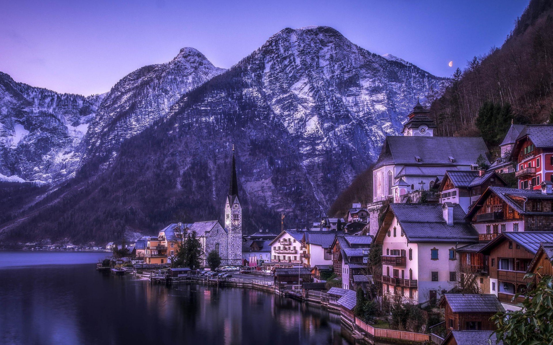 HD PC desktop wallpaper: Hallstatt lakeside village with man-made houses and church spire at dusk, alpine mountains reflected in calm water.
