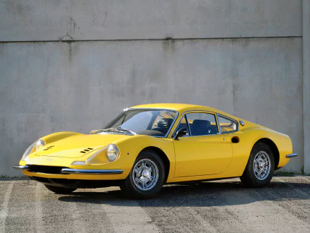 Yellow Ferrari Dino 206 GT sports car parked by a concrete wall — classic Ferrari vehicle, HD PC desktop wallpaper and background.