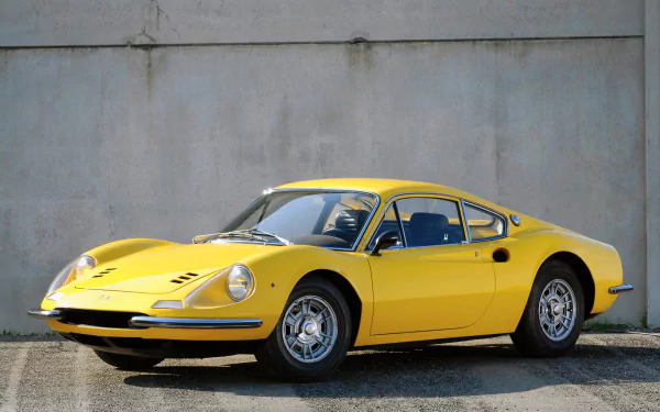 Yellow Ferrari Dino 206 GT sports car parked by a concrete wall — classic Ferrari vehicle, HD PC desktop wallpaper and background.