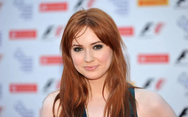 HD desktop wallpaper featuring Scottish actress and celebrity Karen Gillan with red hair and a subtle smile at a public event backdrop.