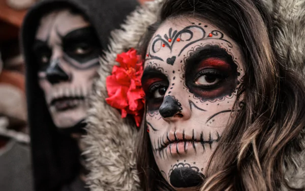 Artistic sugar skull face paint on a woman with a red flower in her hair, captured in stunning 4K Ultra HD for a striking PC desktop wallpaper.