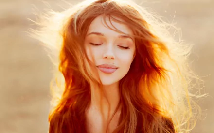 HD desktop wallpaper featuring a woman model with long, flowing hair and a serene expression, bathed in warm, golden sunlight.