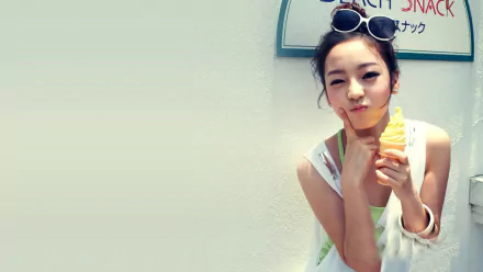 HD PC desktop wallpaper with Korean K-pop music vibe (tag: KARA) — young woman in sunglasses enjoying an ice cream cone against a pale wall.