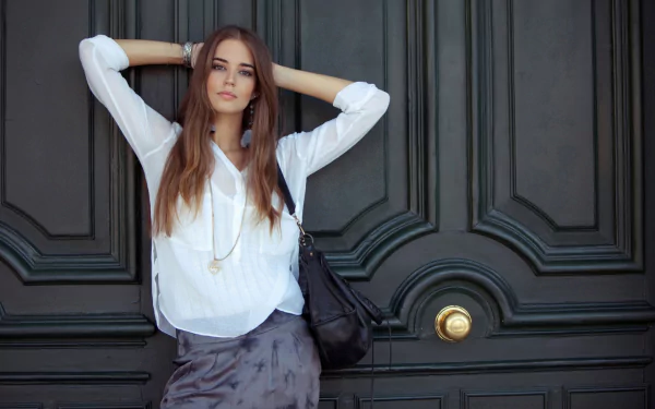 HD desktop wallpaper featuring Spanish woman Clara Alonso posing confidently against a dark ornate door background.