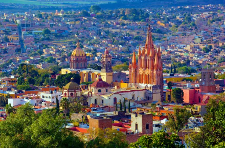 Vibrant cityscape of San Miguel de Allende in Mexico's Bajio region, featuring historic church architecture amidst colorful buildings under a clear sky.