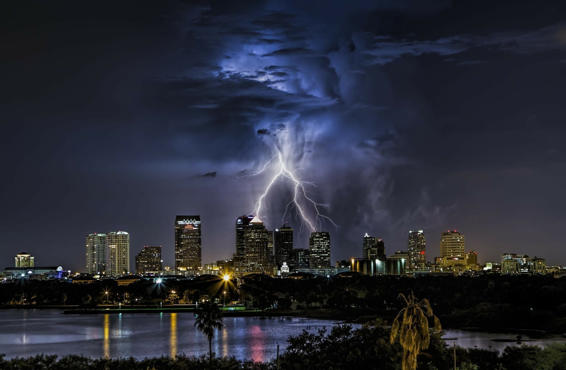 HD PC desktop wallpaper: Lightning over Tampa, Florida — dramatic storm above a man-made city skyline with reflections on water.