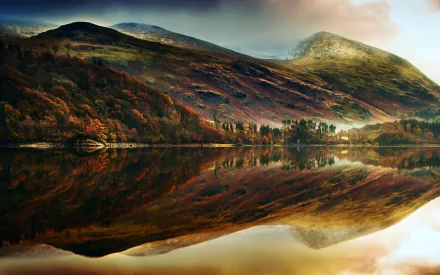 HD desktop wallpaper of late autumn mountain scenery with vibrant fall foliage reflected clearly in calm water under a moody sky.