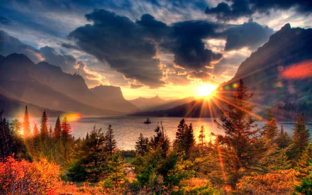 HD desktop wallpaper of Saint Mary Lake at sunset, showcasing vibrant autumn foliage, dramatic clouds, and sun rays piercing through mountain peaks in a stunning nature scene.
