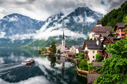 A serene view of Hallstatt, Austria, featuring misty mountains reflected in a tranquil lake, complemented by charming man-made structures along the shoreline.