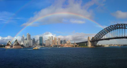 HD wallpaper of Sydney Harbour showcasing the Sydney Opera House, Sydney Harbour Bridge, and a vibrant rainbow arching over the city skyline in Australia.
