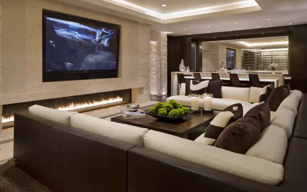 A modern living room features a large sofa, stylish pillows, a coffee table, a sleek television, and a cozy fireplace, creating an inviting atmosphere for relaxation.