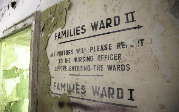 5K Ultra HD PC wallpaper: HDR photo of an urban ruin in Germany — rusted, peeling hospital wall stenciled 'Families Ward II', green-lit doorway in a decayed man-made interior.