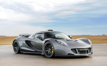 A striking silver Hennessey Venom GT supercar, showcasing its sleek design and powerful stance against a backdrop of open skies, serves as an impressive HD wallpaper.