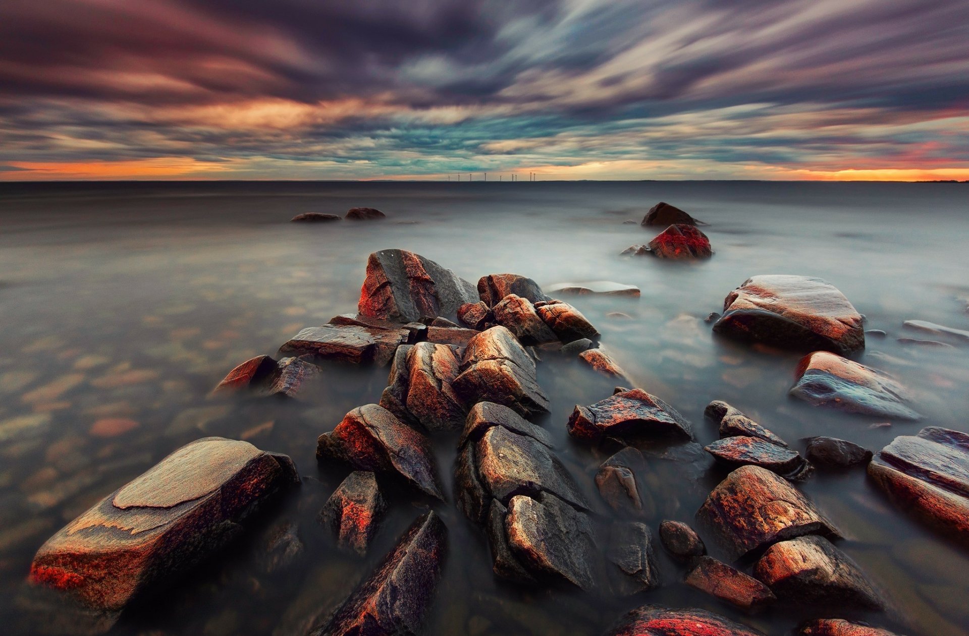Twilight seashore nature scene with dramatic cloud-streaked sky, smooth misty water and foreground rocks — HD PC desktop wallpaper and background.