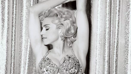 Black-and-white portrait of a blonde pop singer in a vintage sequined bustier, arms raised before a shimmering curtain — music-themed HD PC desktop wallpaper and background.