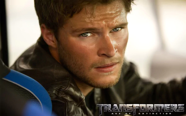 Jack Reynor captures a tense moment from Transformers: Age of Extinction in this HD movie wallpaper, showcasing his intense gaze and rugged look.