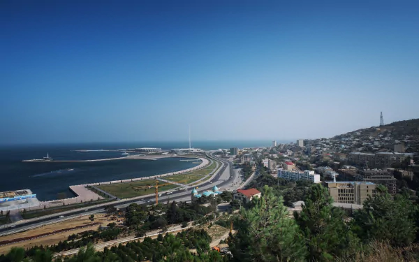 Aerial view of Baku, Azerbaijan coastline along the Caspian Sea with man-made waterfront, curved highway and cityscape — 2K Quad HD PC desktop wallpaper/background.