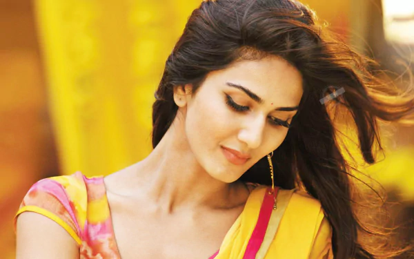 HD desktop wallpaper featuring Bollywood celebrity Vaani Kapoor with a serene expression and flowing hair against a vibrant yellow background.