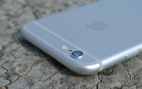 Close-up of a silver iPhone camera and Apple logo on cracked stone, styled as a 4K Ultra HD PC desktop wallpaper background highlighting technology.