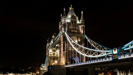A stunning view of Tower Bridge at night, showcasing its illuminated structure against a dark sky. This 4K Ultra HD wallpaper captures London's iconic man-made landmark.