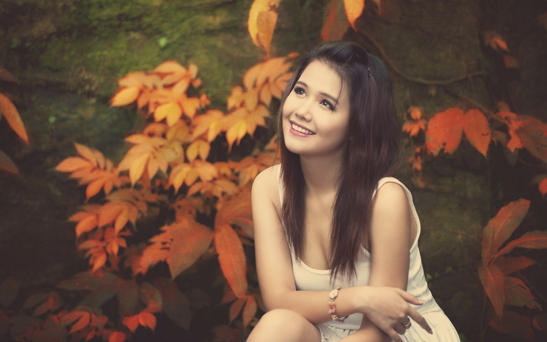HD desktop wallpaper featuring a woman sitting amidst vibrant autumn foliage, exuding a serene and contemplative mood.