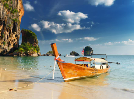 4K Ultra HD wallpaper of a traditional wooden boat anchored on the clear waters of Phuket, Thailand, with limestone cliffs and blue skies in the background.