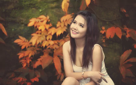 HD desktop wallpaper featuring a woman sitting amidst vibrant autumn foliage, exuding a serene and contemplative mood.