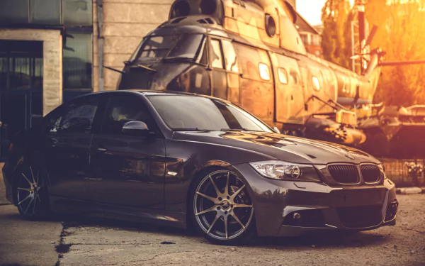 HD desktop wallpaper featuring a sleek BMW car parked in front of a helicopter, capturing a dynamic and adventurous vibe.