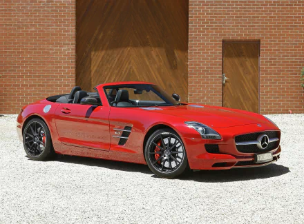 Red Mercedes-Benz SLS AMG roadster parked in front of a brick wall, captured in high-definition as a sleek PC desktop wallpaper and background.