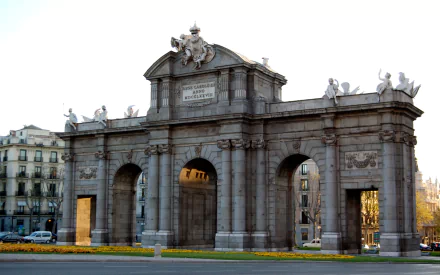Man-made Puerta de Alcalá in Madrid, frontal view with warm evening light and ornamental sculptures — HD PC desktop wallpaper and background.