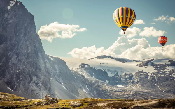 4K Ultra HD desktop wallpaper showcasing colorful hot air balloons floating above a rugged mountain landscape under a bright, partly cloudy sky.