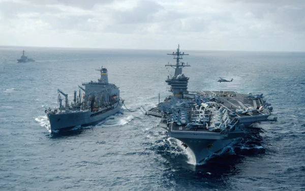 Aerial view of the USS Carl Vinson (CVN-70), an aircraft carrier, alongside a supply ship in open water, showcasing military maritime operations. 4K Ultra HD wallpaper.
