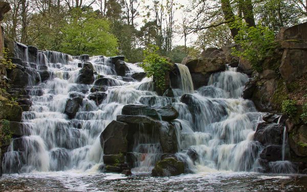A stunning close-up of a cascading waterfall surrounded by lush greenery, capturing the serene beauty of nature. A captivating 4K Ultra HD wallpaper for any desktop background.