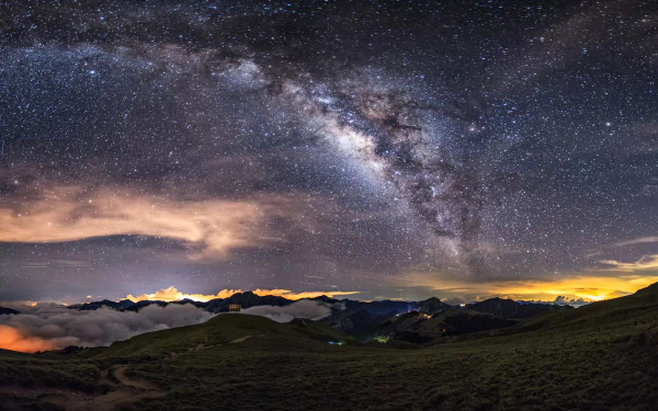 HD desktop wallpaper depicting the Milky Way across a starry night sky, set over a tranquil natural landscape with rolling hills. The sky's intricate detail gives it a Sci-Fi essence.