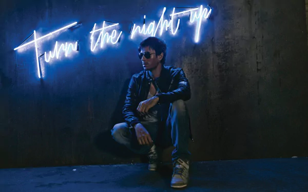 A striking HD desktop wallpaper featuring Enrique Iglesias, posed against a dark wall illuminated by neon text that reads Turn the night up.