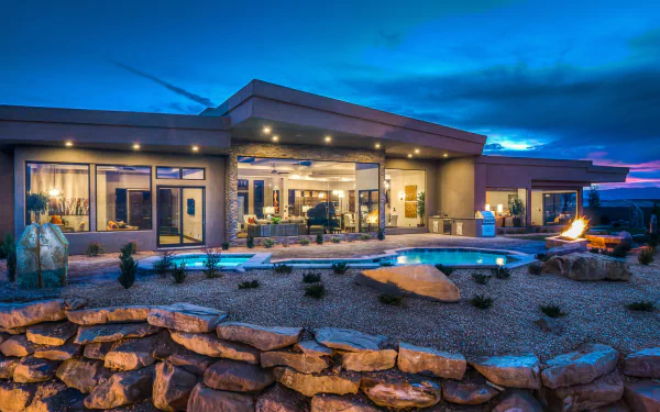 Luxury modern house in Utah with a landscaped garden and illuminated pool under a vibrant evening sky, captured in HD for a desktop wallpaper background.