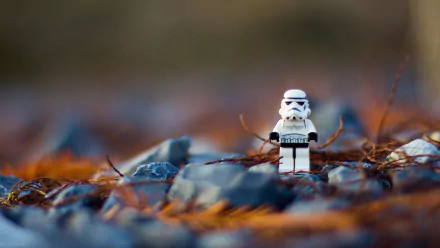 HD desktop wallpaper featuring a man-made LEGO stormtrooper figure standing on rocky ground with blurred natural background.