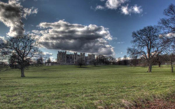 HD PC desktop wallpaper featuring the man-made structure of Raby Castle under a dramatic sky, framed by trees on a vast green lawn.