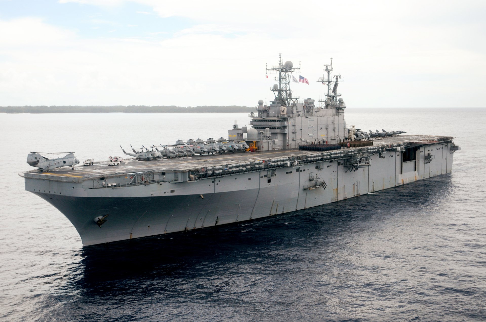 An HD image of the USS Peleliu (LHA-5), an amphibious assault ship from World War II, showcasing its helicopter deck and military design against a tranquil sea backdrop.