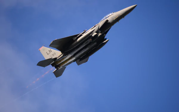 A McDonnell Douglas F-15E Strike Eagle jet fighter soars through a blue sky, showcasing its powerful design and military presence as an impressive aircraft wallpaper.