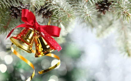 HD Christmas wallpaper featuring golden bells adorned with a red ribbon, hanging from a festive tree branch decorated with pinecones. The background has a bokeh effect, enhancing the holiday atmosphere.
