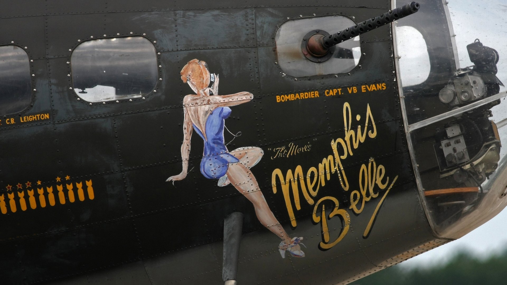 HD PC desktop wallpaper and background showing military aircraft nose art: Memphis Belle pinup painted on a bomber fuselage beside a gun turret.