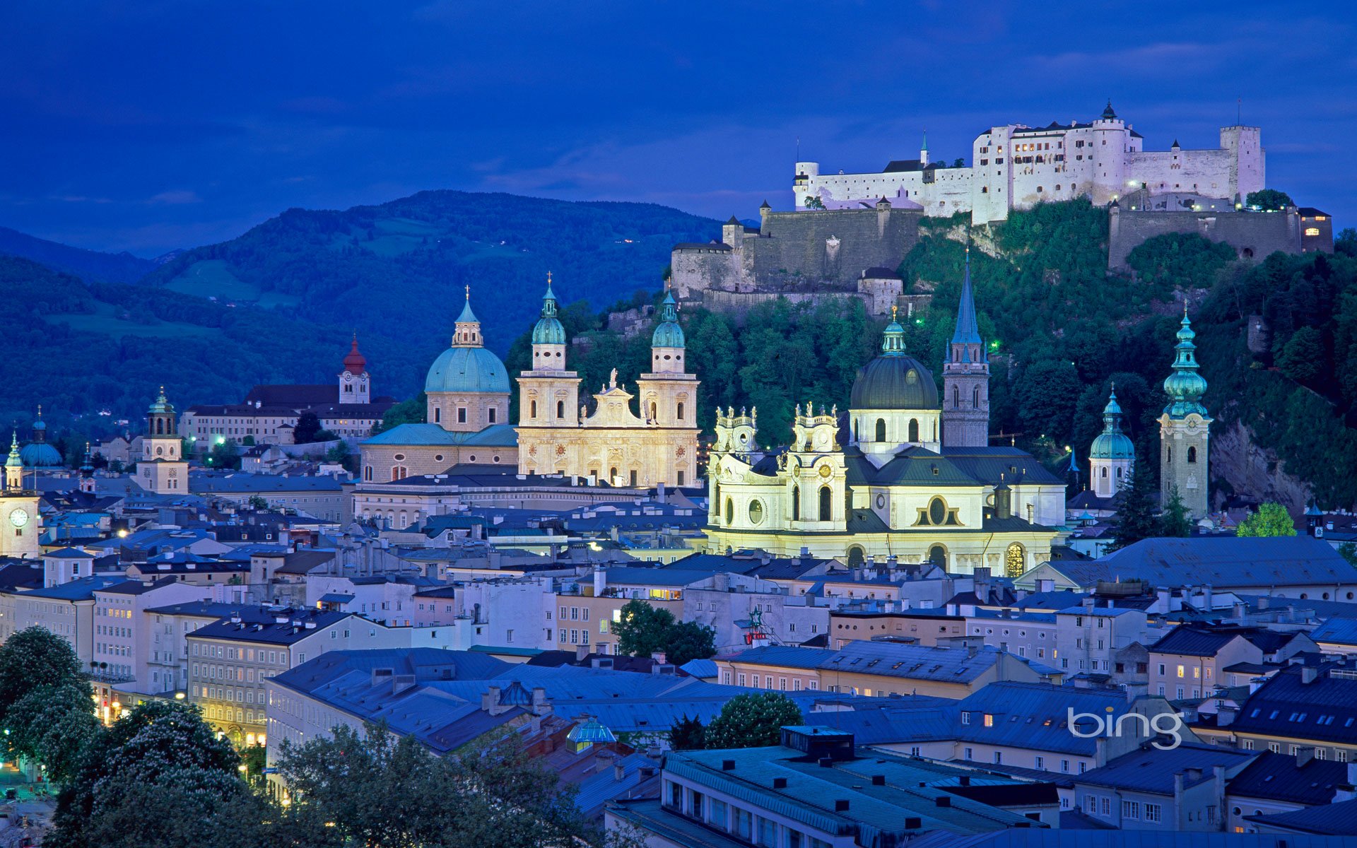 Night view of Salzburg, Austria showcasing the illuminated historic town and the fortress perched on a hill, captured as an HD desktop wallpaper and background.
