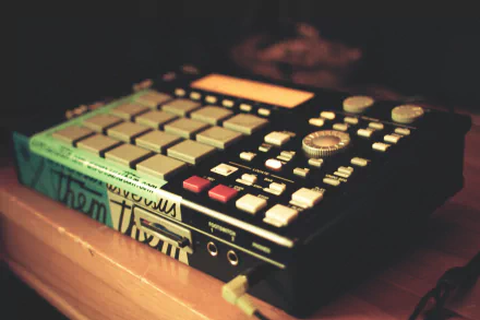 HD desktop wallpaper featuring a close-up of a beat-making music sampler on a wooden surface.