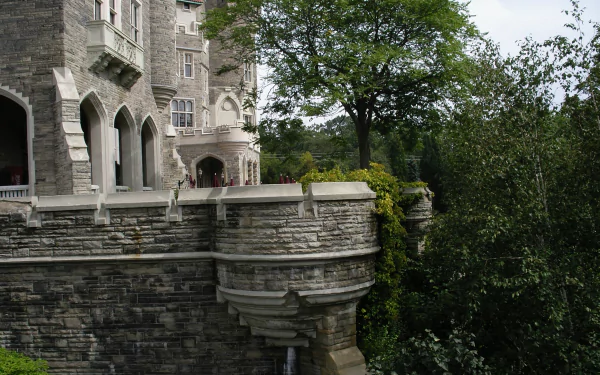 Stone terrace and turrets of Casa Loma rising above verdant trees, man-made Gothic Revival architecture captured as a 2K Quad HD PC desktop wallpaper and background.